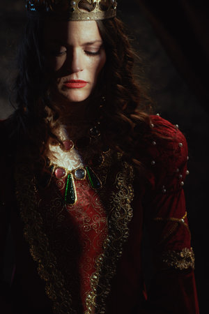 medieval queen in red dress with crown on dark gray background.の写真素材