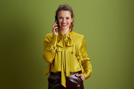 smiling trendy woman on green background talking on a smartphone.の写真素材