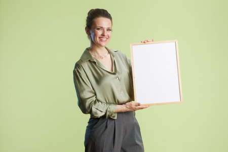 A smiling woman presents a blank white sign with a wood frame, ideal for business, advertising, or positive messaging.の写真素材