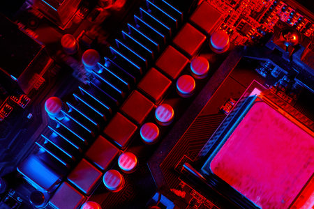 Close-up of a computer motherboard under red and blue lights, highlighting heat sinks and capacitors...