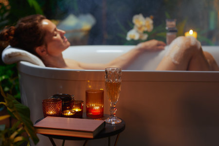A woman with eyes closed finds tranquility in a steaming white bathtub, her head resting on a towel....