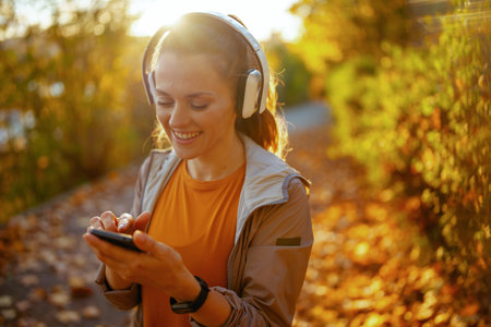 Hello autumn. smiling stylish woman in fitness clothes in the park with headphones.