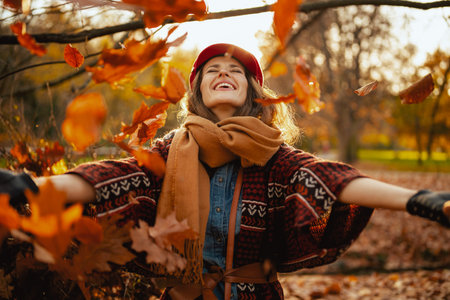 Hello autumn. happy elegant 40 years old woman with scarf rejoicing in the city park.の写真素材