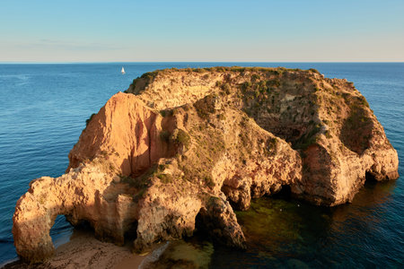 Secluded limestone island and beach Praia JoÃ£o de Arens in Algarve region, Portugal
