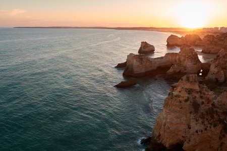 Amazing sunset over unique limestone rocks and secluded beaches near Alvor village, Portugalの写真素材