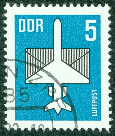 DDR - CIRCA 1983  A stamp printed in DDR, shows a stylized airplane with an envelope, circa 1983の写真素材