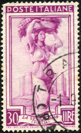 ITALY - CIRCA 1950: A stamp printed in Italy, shows Woman carrying grapes, series work of Italians, circa 1950のeditorial素材