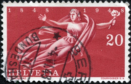 SWITZERLAND - CIRCA 1948  A stamp printed in Switzerland, is dedicated to the 100th anniversary of the state, is shown flying Helvetia with a torch, circa 1948の写真素材