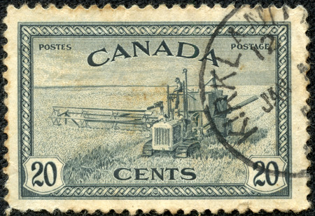CANADA - CIRCA 1933: A stamp printed in Canada shows wheat harvest and 1930s style combine, circa 1933のeditorial素材