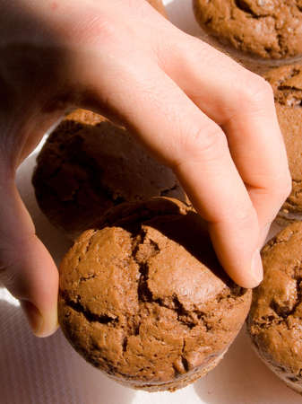 Hand picking up a chocolate muffinの写真素材
