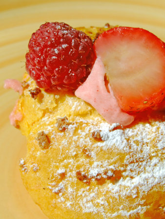 Puff dough filled with berries cream, decorated with strawberry, raspberry and icing sugarの写真素材