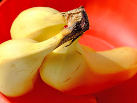 Three ripe bananas in a red plastic basketの写真素材