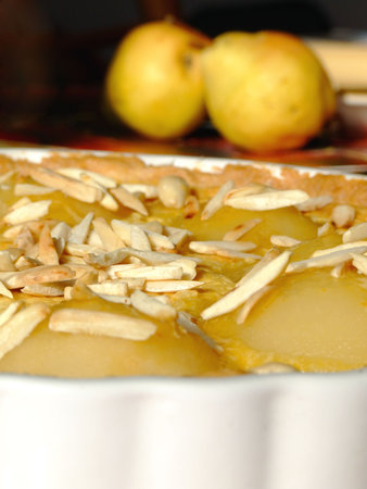 Close-up of a homemade tart Bourdaloue with pears, almond cream and vanilla custard and some ingredients besidesの写真素材