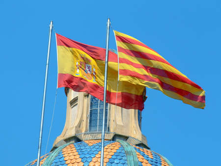 Spanish and Catalan flags waving in the blue skyの写真素材