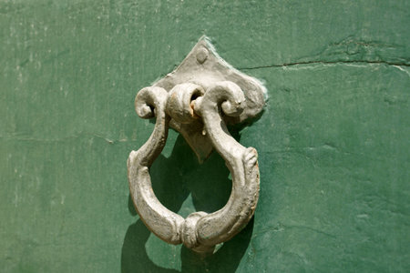 Ancient bronze door knocker over green painted woodの写真素材