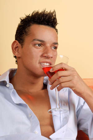 Portrait of a smiling young latin man holding a red cocktailの写真素材