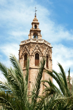 El Miguelete, the gothic bell tower of Valencia Cathedral in Spain, among palms. The Cathedral was built between 1252 and 1482 on the site of a mosque and previosly a roman temple dedicated to Diana.の写真素材