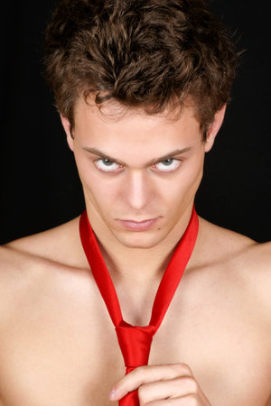 Portrait of a sexy young man with red silk tie over a black background.の写真素材