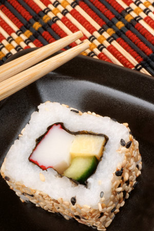 Japanese maki sushi on a black tray with chopsticks, ready to be eaten. Selective focus.の写真素材