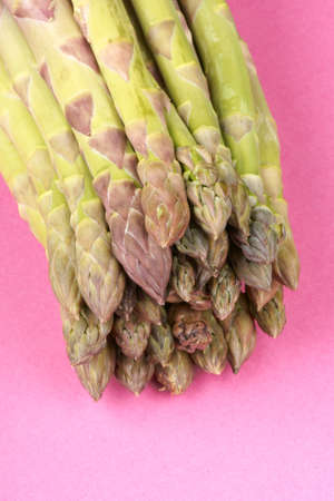 Close-up of some raw green asparagus over a pink paper backgroundの写真素材