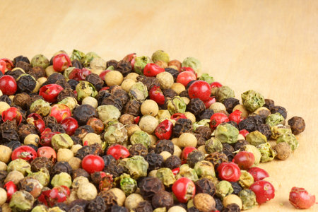 Four seasons pepper grains over a wooden background with copy space