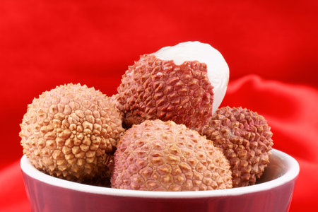 Close-up of some litchis (lychee) over a red background.