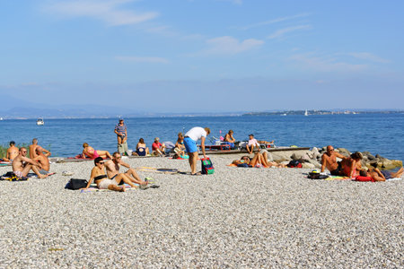 Padenghe sul Garda, Italy - September 13, 2014: people sunbathing on pebble shore at Lake Garda in Padenghe sul Garda, Lombardy, Italyのeditorial素材
