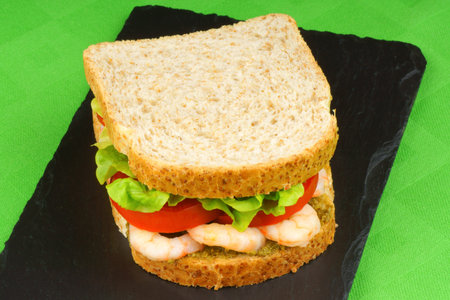 Close-up of a sandwich with shrimps, pesto, lettuce and tomatoの写真素材