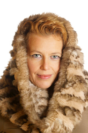 Portrait of a caucasian blond woman with blue eyes wearing an ecologic fur hood over a white background.の写真素材
