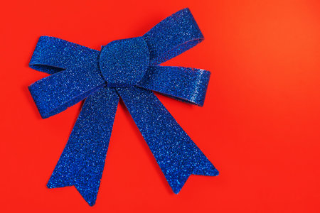 Christmas card, copy space. Christmas composition blue glitter bow on a red background.の写真素材
