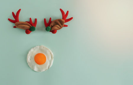 Creative flat lay concept of a reindeer with a poached egg instead of a nose against light pastel mint green color. Christmas and food theme idea with copy space.の写真素材