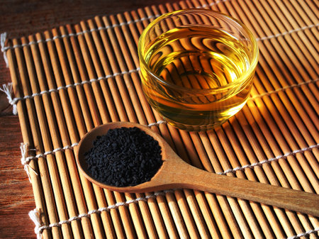 Black sesame seeds in wooden spoon and a glass of oil.の写真素材