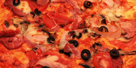 Delicious pizza with cheese, bacon, tomatoes and olives. Background with pizza.の写真素材