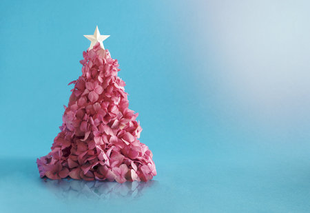 Christmas tree made of a small pink flowerers against light blue background. Minimal flat lay composition.の写真素材