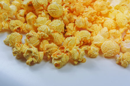 Lots of Butter Flavored Popcorn scattered on a white backgroundの写真素材