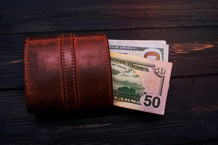 Financial and business concept. Dollars in a brown wallet on a black cement background.の写真素材