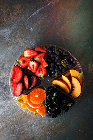 Assorted fruit and berries on a plate with strawberry, peaches, blackberry and orangeの写真素材