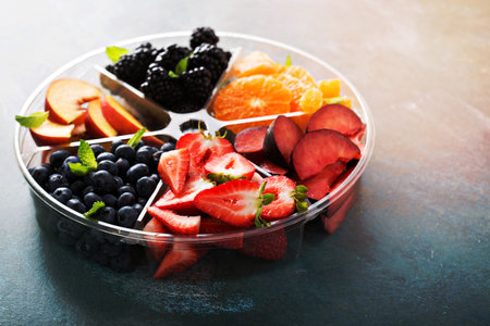 Assorted fruit and berries on a plate with strawberry, peaches, blackberry and orangeの写真素材