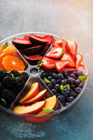Assorted fruit and berries on a plate with strawberry, peaches, blackberry and orangeの写真素材