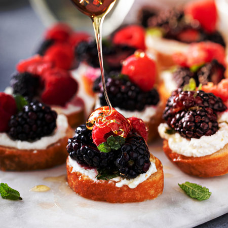 Berry and goat cheese bruschetta with fresh mint and honey, drizzling with honeyの写真素材