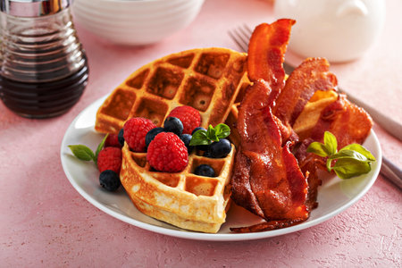 Belgian waffles with crispy bacon and fresh berries for breakfast, served with maple syrupの写真素材