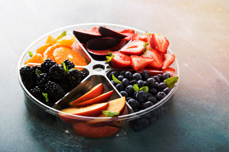 Assorted fruit and berries on a plate with strawberry, peaches, blackberry and orangeの写真素材