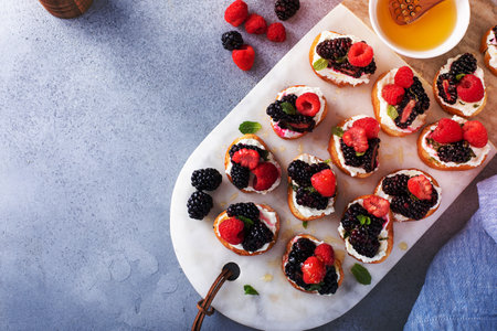 Berry and goat cheese bruschetta with fresh mint and honey, top viewの写真素材