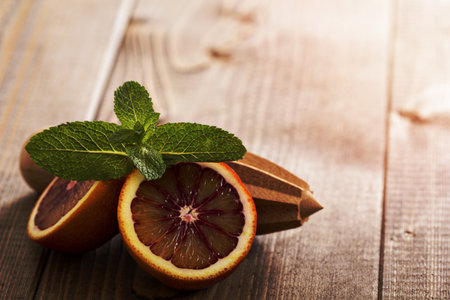 Blood oranges with fresh mint and wooden reamerの写真素材
