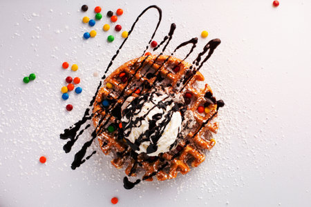 Belgian waffle with a scoop of ice cream, whipped cream and chocolate syrupの写真素材