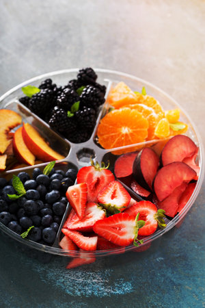 Assorted fruit and berries on a plate with strawberry, peaches, blackberry and orangeの写真素材