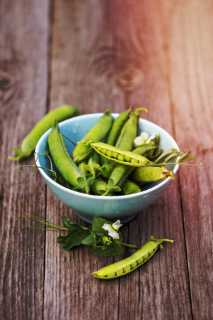 Fresh green peas in a bowl on a wooden tableの写真素材