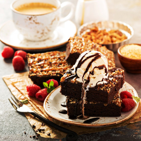 Fudgy brownies with nuts, chocolate and caramel syrup and a scoop of ice creamの写真素材