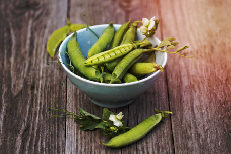 Fresh green peas in a bowl on a wooden tableの写真素材