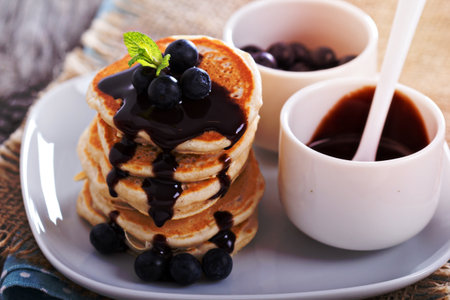 Eggless pancakes for breakfast with blueberries and chocolate sauceの写真素材
